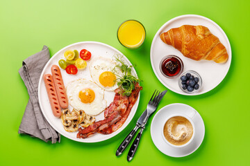 A classic breakfast plate featuring sunny-side-up eggs, crispy bacon, sausages, and fresh tomatoes