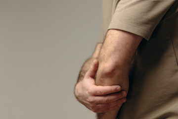 Man suffers from elbow pain due to negative impact of long-term computer work, bad posture,...