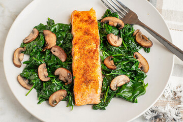 seasoned salmon resting on  spinach and mushrooms