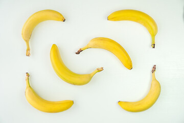 Top view photo of unpeeled yellow bananas on white background table