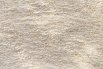 A macro shot of beige feathered textile with metallic threads. 