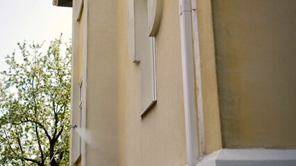 The process of cleaning the exterior of a house using water and solution. A man using a pressure washer on the siding of a house. Cleaning and maintenance concept.