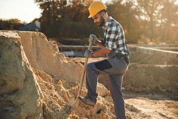Soil, digging with a shovel. Worker is on the construction site at daytime