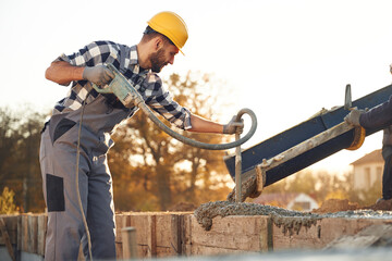 Concrete on the foundation of the house. Worker is on the construction site at daytime