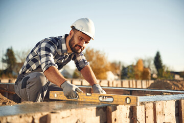 Tool for measuring leveling of surface. Worker is on the construction site at daytime