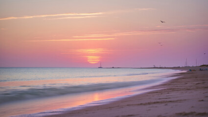 Fototapeta premium Sunset at the beach with soft waves and tranquil colors during evening hours
