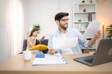 Fototapeta premium Portrait of a young freelancer smiling while working online via laptop at home with his girlfriend