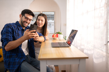 Portrait of a young freelancer smiling while working online via laptop at home with his girlfriend