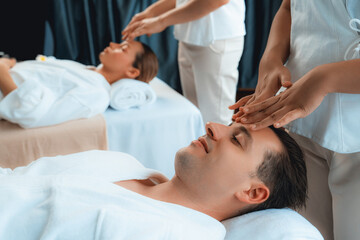 Fototapeta premium Caucasian couple enjoying relaxing anti-stress head massage and pampering facial beauty skin recreation leisure in dayspa modern light ambient at luxury resort or hotel spa salon. Quiescent