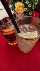 Refreshing summer drinks with lemon and ice on red tablecloth
