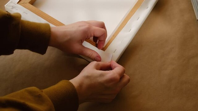 Framer stretching canvas on wooden stretcher bars. Print on canvas.