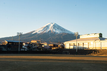 Monte Fuji visto de um campo de futebol de areia com casas ao fundo © Caio Viniccio
