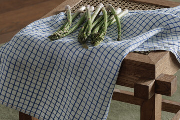 Fresh asparagus on rattan stool with linen tea towel. Healthy lifestyle concept