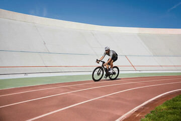 Healthy man cyclist exercising on bicycle on sprint track