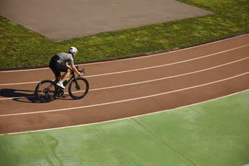 Bicyclist enjoying training cycling on open velodrome track view from afar