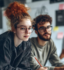 Smiling and working happily together, two young professionals in a modern office represent the productivity and collaboration of a modern business environment.