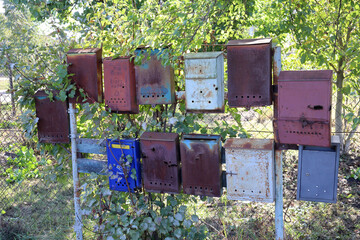A bunch of old rusty mailboxes on a fence