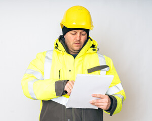 a man in a yellow working winter jacket, yellow safety helmet with papers in his hands. High quality photo