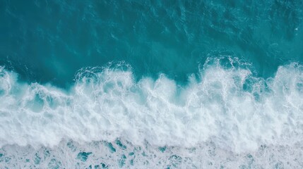Aerial view of ocean waves crashing on a sandy beach in vibrant turquoise waters