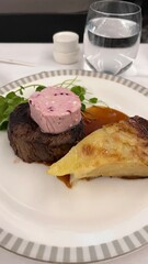 Premium Steak Dinner with Gourmet Sides: A perfectly cooked filet mignon with berry butter, fresh greens, and creamy potato gratin, elegantly plated for a luxurious dining experience.