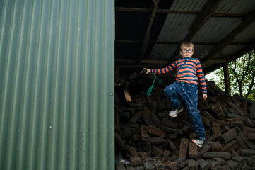 Young Boy Playing and Hiding in Pile of Peat Bricks at Home