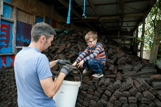 Father and Son Filling Out Bucket with Bricks in Garden