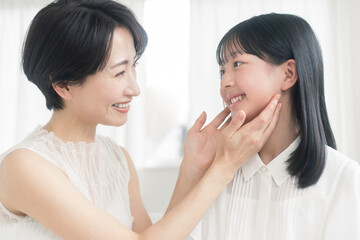 母娘のビューティーイメージ/娘が母親の頬を触っている。