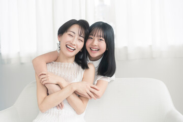 笑顔の親子/娘が母に後ろから抱きついている。