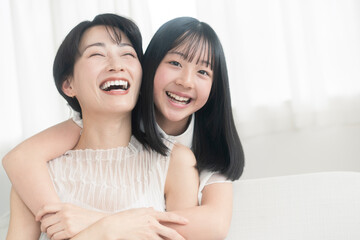 笑顔の親子/娘が母に後ろから抱きついている。
