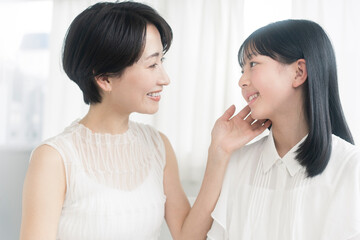 母娘のビューティーイメージ/娘が母親の頬を触っている。