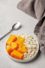Healthy breakfast. Cottage cheese with pieces of pumpkin in orange sauce in a plate on the table.