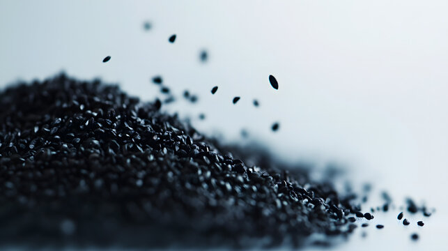 Black cumin seeds scattered in a thin layer on a white surface, showing their deep black color and natural texture.Black cumin seeds scattered in a thin layer on a white surface, showing their deep bl