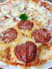 Thin and crispy pizza, divided in half, topped with pepperoni and sausage and cheese, Italian style, eight slices, placed on a wooden tray.