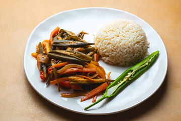 African cuisine: stewed okra with vegetables and peppers served with white rice. Traditional African recipes, front view