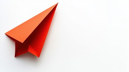 A bright orange paper airplane rests on a white background, showcasing creativity and fun