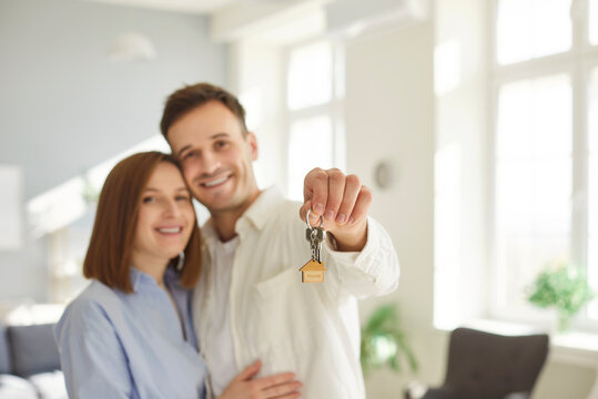 Young happy couple showing keys, moving day holiday, new shared home or dwelling, man and woman spouses feel overjoyed moving relocating to own house, real estate clients enjoy good flat, room 