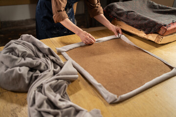 Woman upholster using a staple gun to reupholster armchair seat