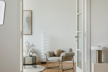  A sleek modern lounge area with a boucle armchair, a sculptural lamp, and delicate decorative...