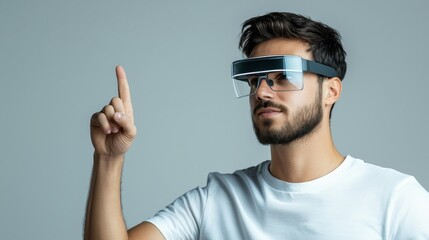 Man in t-shirt using augmented reality headset, interacting with virtual interface, futuristic digital experience on gray background.