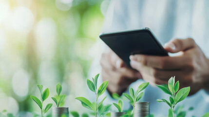 Green investment concept with hands holding smartphone above growing plants on coins showing sustainability