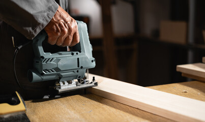 carpenter working with an electric jigsaw in carpentry workshop