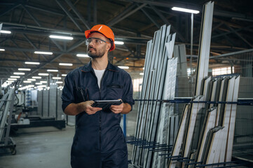 With digital tablet. Man is working in the modern factory