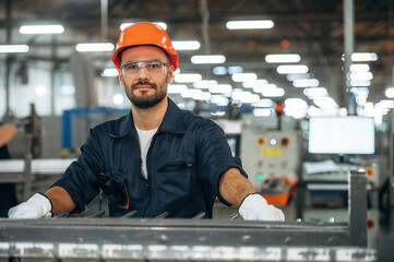 Portrait, front view, standing. Man is working in the modern factory