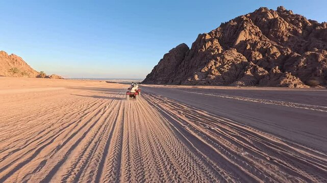 Quad bike ride through the desert near Sharm el Sheikh, Egypt.Adventures of desert off-road on ATV.Sand and Sand Borkhan. Rock and sunset. Quad Cycle Travel. Excursion with people.