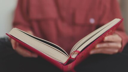 Close-up of a woman turning the page of a book, a girl relaxing at home with a book in her hands. the girl is reading.