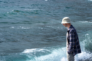 Introspective man stands knee-deep in turquoise waters, Coastal wanderer in checkered shirt and...