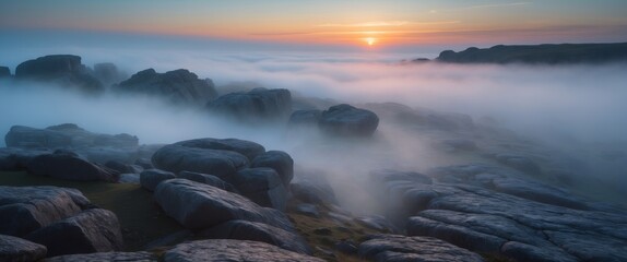 Stunning sunrise over a rocky landscape shrouded in mist reveals nature's tranquil beauty at dawn