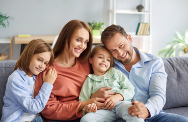 Portrait of a happy parents and children embracing on the couch at home, sharing affection and bonding. The family enjoys leisure time together, reflecting their love and connection.