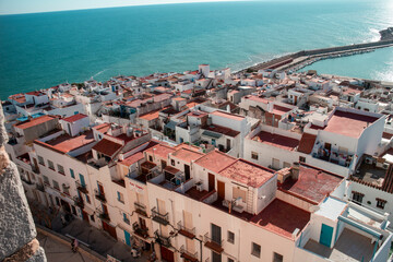 A picturesque aerial view of a coastal town featuring whitewashed buildings and red roofs by the sea.