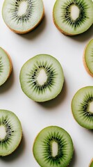 Fototapeta premium Kiwi slices are arranged on a white surface, showcasing their vivid green color and pattern